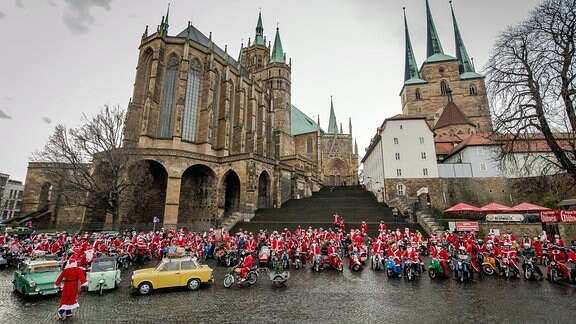 Weihnachtsmänner stehen vor den Domstufen in Erfurt.