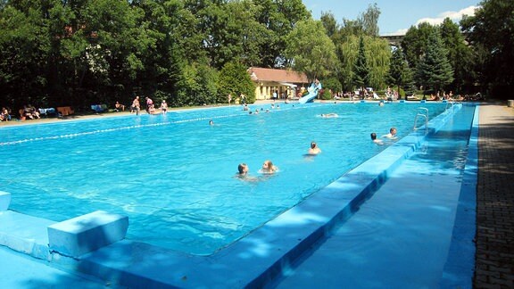 Schwimmbecken mit Rutsche und schattigen Liegeplätzen im Freibad Stadtilm. 