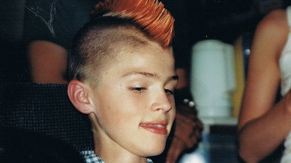 Ein Jugendlicher mit einem roten Irokesenhaarschnitt. 