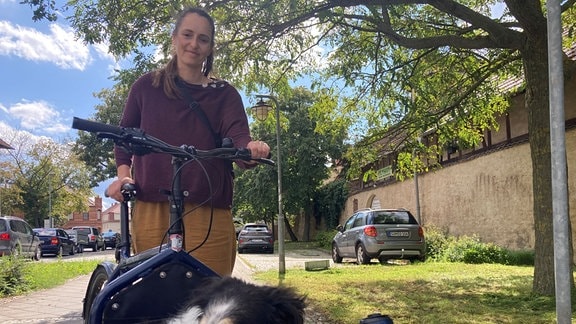 Eine Radfahrerin nimmt ihren Hund im Lastenrad mit.