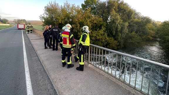Polizisten und Feuerwehrleute stehen auf einer Brücke