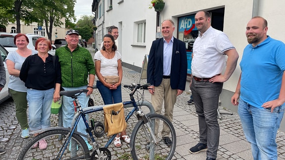 Stefan Schröder (AfD) steht mit anderen Leuten auf dem Gehweg