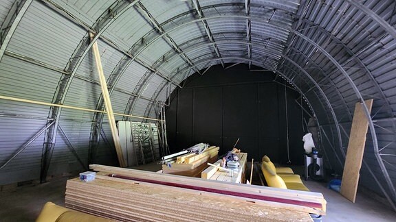 Eine Halle aus Wellblech in der Holzbretter liegen