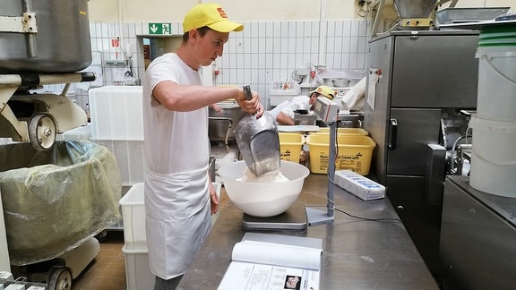 Mann in Bäckerei wiegt Mehl ab