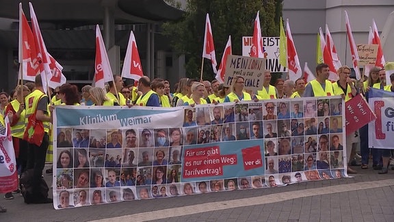 Eine Menschenmenge in gelben Warnwesten halten ein Banner und Verdi-Flaggen