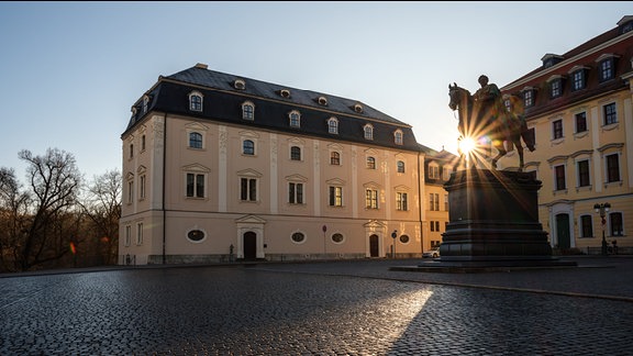 Die Sonne geht hinter einem historischen Schloss auf.