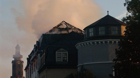 Rauch steigt über einem historischen Schloss auf, in dem sich eine Bibliothek befindet.