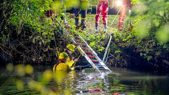 Menschen steigen bei Nacht in einen Fluss.