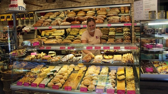 Eine Verkäuferin legt Ware in eine Bäckerei-Auslage