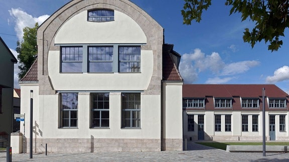Blick auf die Fassade der Bauhaus-Universität Weimar, ein zweistöckiges Gebäude mit heller Fassade und großen Fenstern. 
