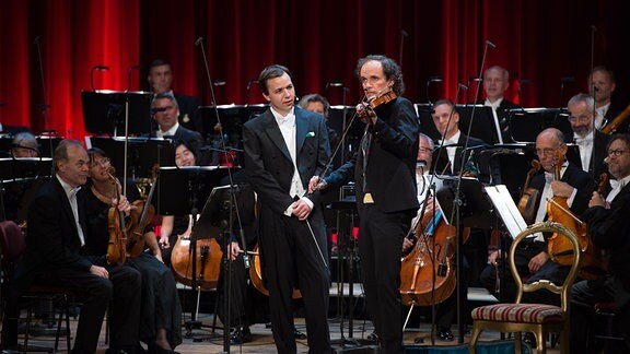 Der Comedian Olaf Schubert, der Dirigent, Dominik Beykirch (l) und das MDR Sinfonieorchester agieren am 11.07.2016 während der Generalprobe der Aufzeichnung "Olaf Schubert und die ziemlich große Oper" auf der Bühne in der Semperoper in Dresden 