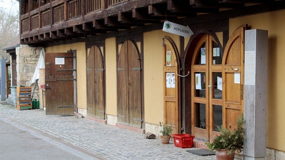 Ein Schild mit der Aufschrift "Hofladen" hängt über einer Tür.