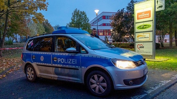 Ein Polizeiauto steht vor einem Schild.