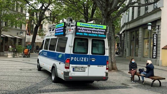 Polizeifahrzeug mit Lautsprechern und Hinweistafel zu Corona in Weimar