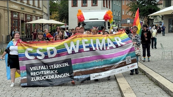 CSD Weimar 2024: Eine Gruppe von Demonstranten hält ein Banner vor sich mit der Aufschrift "CSD Weimar"