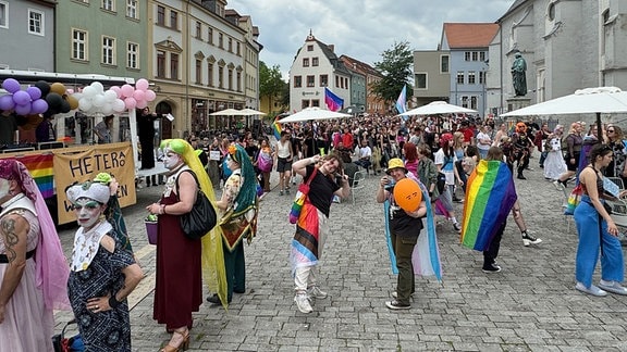 CSD Weimar 2024:  Verkleidete Menschen stehen am Wegesrand während ein bunt-geschmückter Lkw durch die Innenstadt fährt