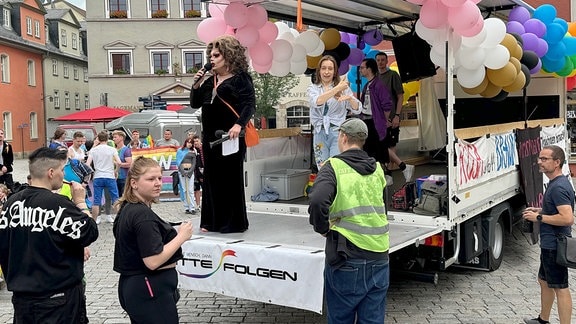 CSD Weimar 2024:  Eine Drag-Queen spricht von einem Lkw zum Publikum.