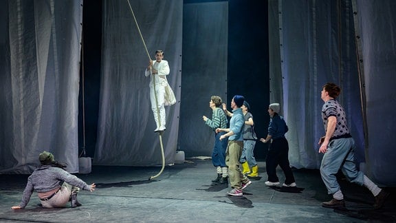 Szene aus "Moby Dick" am DNT Weimar, ein Darsteller lässt sich von einem Seil herab