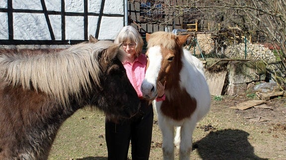 Eugenie Trützschler von Falkenstein auf ihrem Hof mit zwei Pferden