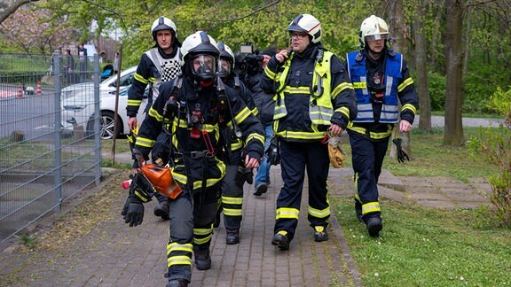 Mehrere Feuerwehrmänner auf einem Fußweg.