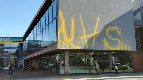 Große gelbe Buchstaben an der Fassade eines Gebäudes.