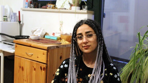 Eine junge Frau mit Brille in ihrer Wohnung.