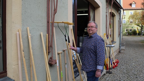 Ein Mann (Matthias Riediger) vor seinem Laden beim Aufräumen