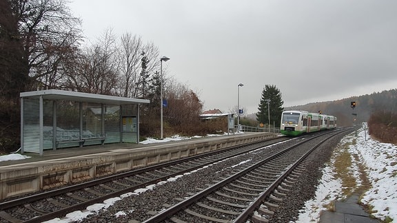 Bahnschienen in Winterlandschaft und ein Zug in der Ferne