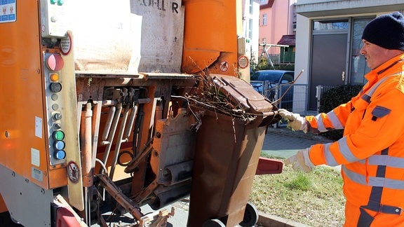 Mitarbeiter der Müllabfuhr leert eine Tonne in eine Müll-Auto.