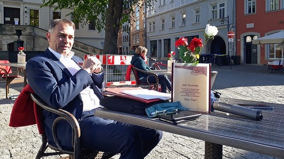 Weimars Oberbürgermeister Peter Kleine an einem Tisch vor einem Bistro
