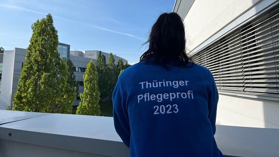 Caroline Plickert trägt eine Jacke mit der Aufschrift "Thüringer Pflegeprofi 2023" auf dem Rücken.