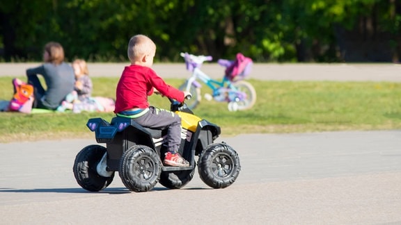 ein Kleinkind auf einem Kinderauto