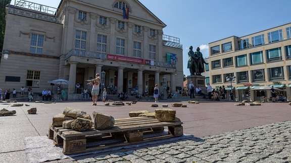 Menschen tragen Steine auf dem Weimarer Theaterplatz.
