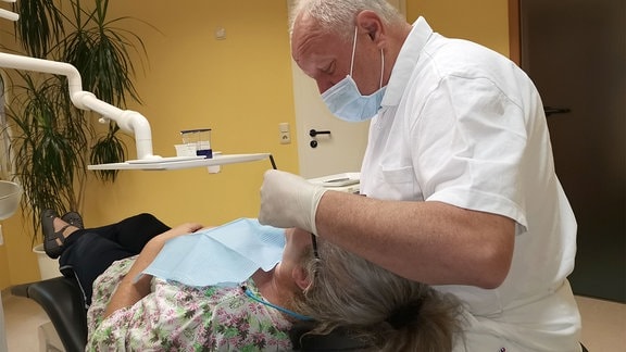 Ein Zahnarzt und eine Patientin in der Zahnarztpraxis bei Untersuchung.