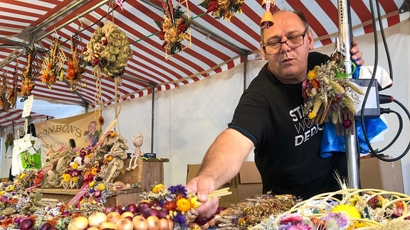 Ein Verkäufer an einem Stand mit verschiedenen Zwiebeln