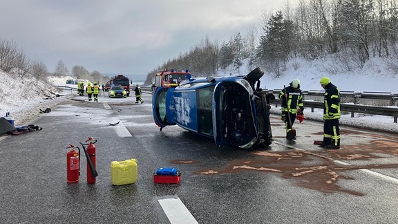 Blaue Auto liegt nach Unfall auf der Autobahn auf der Seite 
