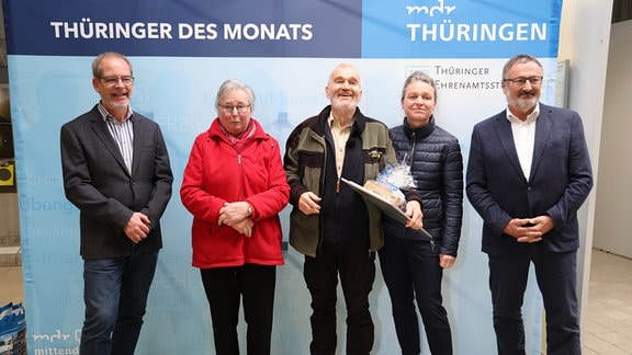 Eine Gruppe von Menschen steht vor einer Wand von MDR THÜRINGEN und der Thüringer Ehrenamtsstiftung und schaut in die Kamera.