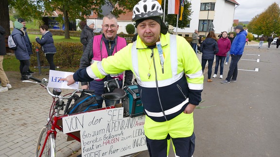 Zwei Männer beim Kirmes-Festumzug in Hausen. Der vordere Mann ist als Anzeigenhauptmeister verkleidet. Im Hintergrund stehen Leute.