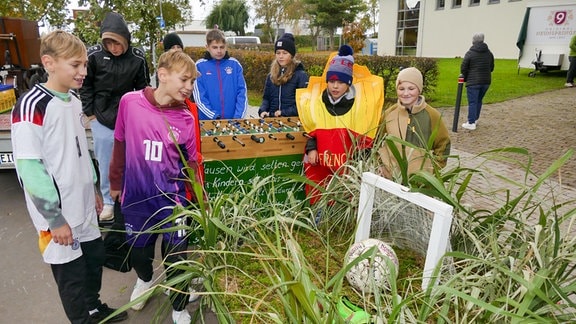 Als Fußballer verkleidete Kinder bei einem Kirmes-Festumzug. Im Vordergrund liegt ein Ball im Gras auf einem Wagen.