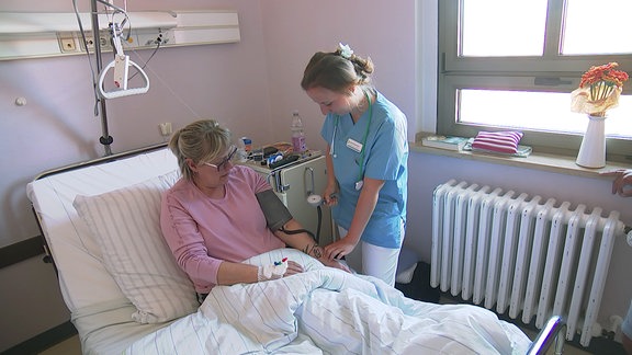 Auszubildende Pflegerin betreut eine Patientin