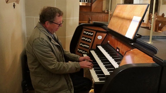 Landrat Werner Henning sitzt an einer Orgel und spielt.