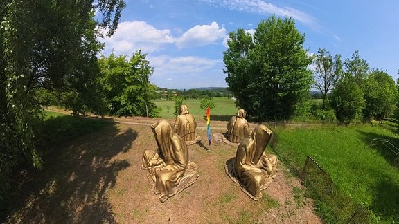 Vier riesige Mönchsfiguren stehen auf einer Rasenfläche