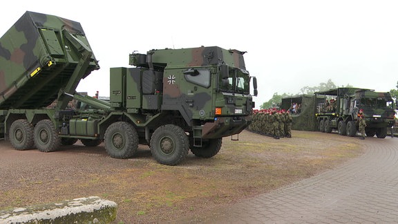 Bundeswehrfahrzeuge und Soldaten stehen auf einem Platz.