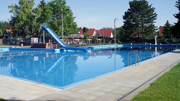 Schwimmbecken, mit Blick auf die blaue Wasserrutsche.