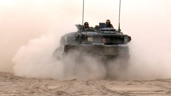 Leopard-2-Panzer fährt durch staubiges Gelände. 