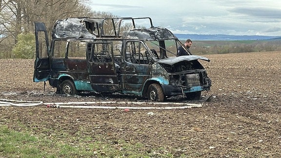 Ein ausgebranntes Autowrack auf einem Feld