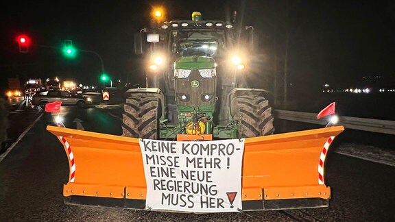 Ein Landwirtschaftsmaschine mit Schieber steht auf der Kreuzung.