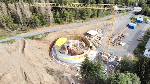 Eine Baustelle mit rundem Fundament und einem Kran von oben gesehen.