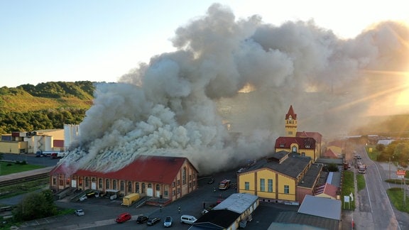 Eine Rauchsäule steigt von einem brennenden Gebäude auf.