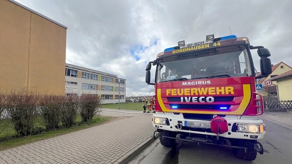 Ein Feuerwehrauto steht vor einem Schulgebäude.